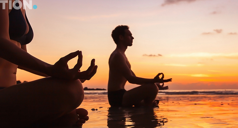 Мужчина и женщина в позе лотоса на закате